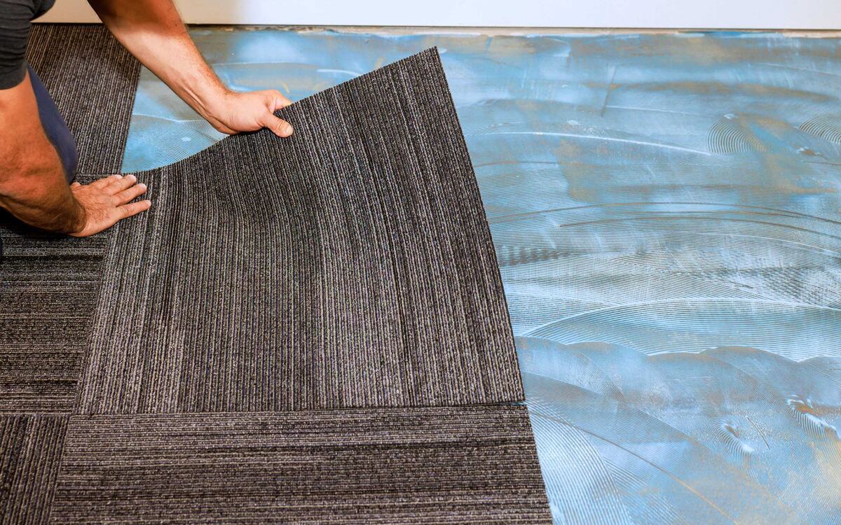 Commercial carpet tile being installed over prepared adhesive